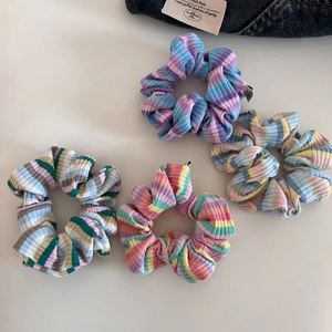 Close-up of four colorful striped knitted scrunchies with ribbed texture on denim