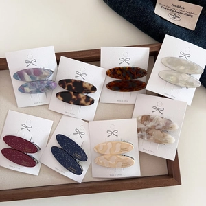 Detailed view of oval acetate hair clips in tortoiseshell and marble patterns on display