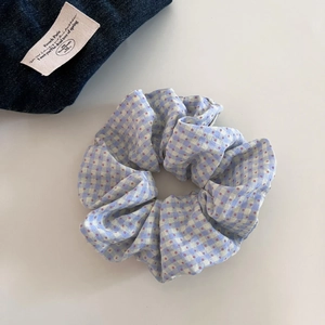 Detail of blue and white plaid scrunchie with red polka dots and soft ruffled texture