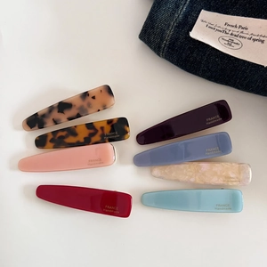 Flat lay of 8 colorful acetate teardrop hair clips with vintage French handmade gold labels