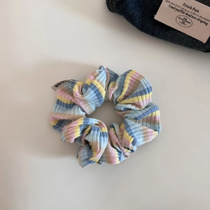 Detailed macro shot of a ribbed fabric scrunchie with macaron colored stripes and logo tag