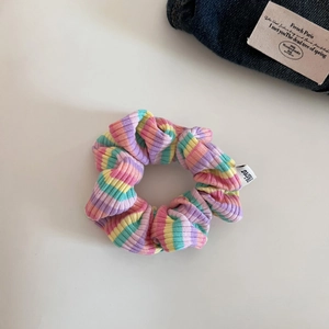 Detailed view of colorful striped scrunchie with pastel ribbed fabric texture and small label