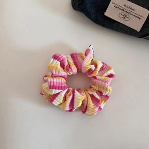 Detailed close-up of a colorful striped knitted scrunchie with soft ribbed fabric textures