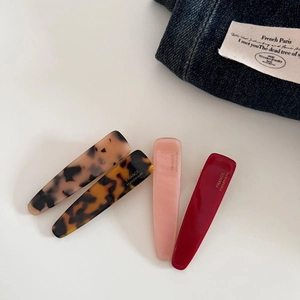 Detail showing four long teardrop hair clips in tortoiseshell and solid colors on white