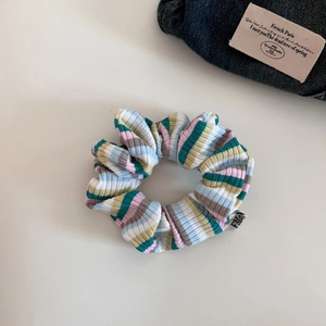 Detail of colorful striped knit scrunchie with elastic texture and woven brand label