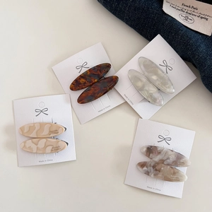 Detailed macro view of four acetate hair clips with tortoiseshell and marble patterns