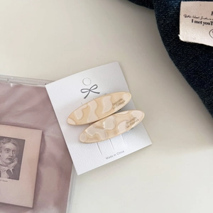 Detail of cream marble pattern oval hair clips with gold lettering on display card