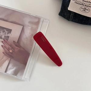 Close-up of a glossy red acetate hair clip featuring a gold France Handmade logo