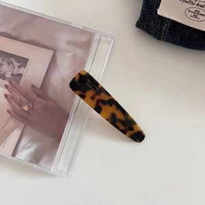 Detailed close-up of tortoise shell pattern acetate hair clip with gold handmade stamping