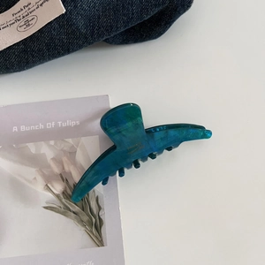 Detailed macro view of acetate hair claw clip featuring blue and green marble texture finish