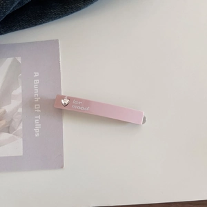 Detailed view of pink acetate hair clip with heart rhinestone and lar mood text