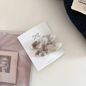 Detail showing two oval marble pattern acetate hair clips on a white display card