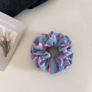 Nahaufnahme eines gestreiften Strick-Scrunchies mit lila, rosa und blauen Mustern