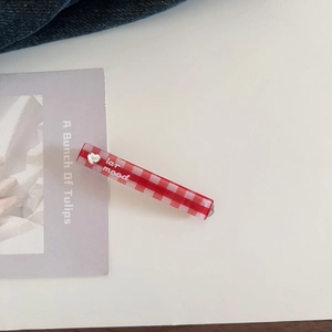 Close-up of red and white checkered hair clip with silver heart and lar mood text