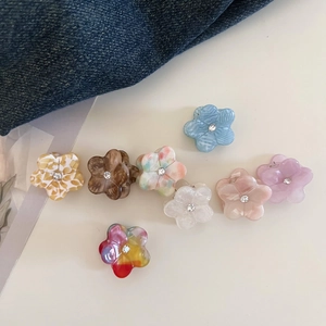Flat lay of small acetate flower hair claws with rhinestones on a blue denim background
