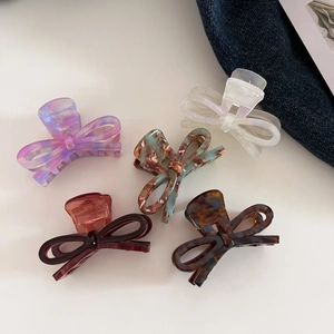 Detailed macro view of five colorful acetate bow hair claws on a clean white background