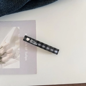 Detail of checkered acetate hair clip with silver heart decoration and artistic lettering