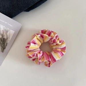 Detailansicht eines gestrickten Haargummis mit rosa, gelben und orangefarbenen Streifen