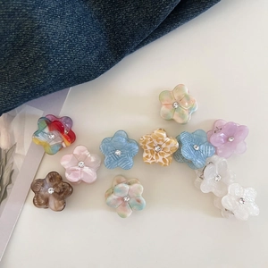 Flat lay of mini floral acetate hair claws in various colors with rhinestone centers