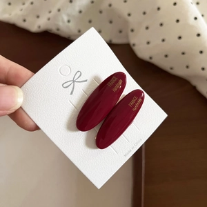 Close-up of deep red oval acetate hair clips with gold France Handmade lettering