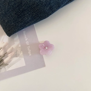 Detail of a purple flower hair claw made of acetate with a central rhinestone accent