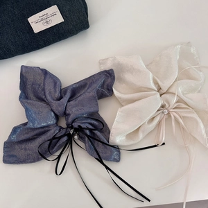 Detailed view of shimmery bow scrunchies with long ribbons and pearl accents