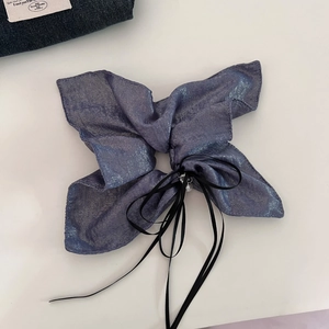 Blue glitter bow scrunchie with long ribbon tassels and pearl detail on plain background