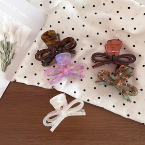 Top view of acetate bow hair claws in five colors including tortoise and pearl white