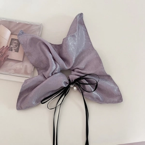 Detail of purple shimmering fabric hair scrunchie with large bow and pearl pendant