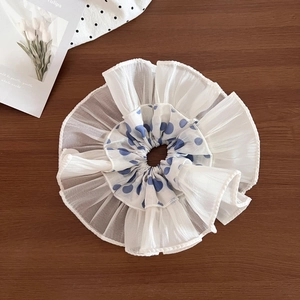Detail of layered white organza scrunchie featuring blue polka dots and ruffles