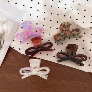 Flat lay of five acetate bow hair claws in various marble and tortoiseshell patterns
