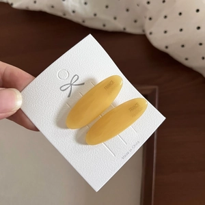 Close-up of yellow oval acetate hair clips with France lettering on white card