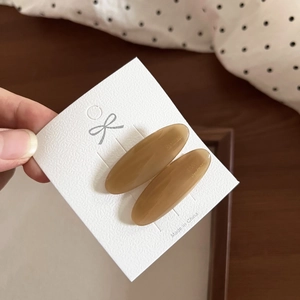 Detailed view of oval amber acetate hair clips on a white presentation card