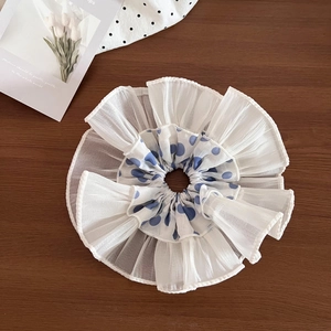 Detailed view of white multi-layer ruffled scrunchie with blue polka dots on dark wood