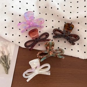 Five assorted acetate bow hair claws featuring marble and tortoiseshell patterns for women