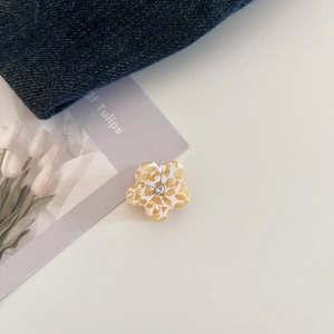Detail of floral acetate hair claw with amber texture and center rhinestone embellishment