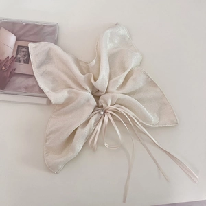 Close-up of cream bow scrunchie with pearlescent fabric, tiny rhinestone and long ribbons