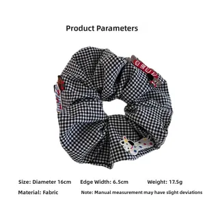 Detail view of a large 16cm black and white checkered scrunchie with dog embroidery