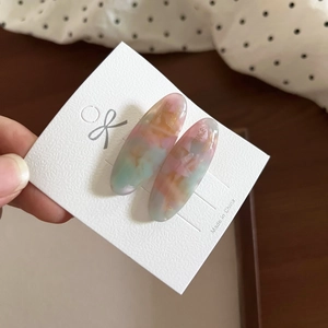 Close-up of vintage oval acetate hair clips with colorful marble texture on card