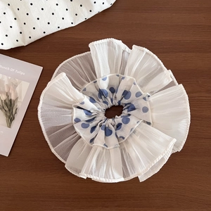 Blue polka dot lace scrunchie with white ruffled edges on a wooden background