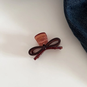 Detailed view of dark brown acetate bow hair claw clip with a glossy resin finish