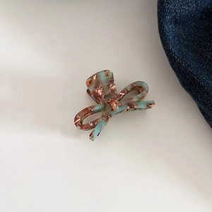 Detail of tortoise shell acetate bow hair claw clip showing glossy marble texture