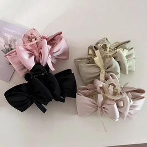 Top view of four elegant satin ribbon bow hair claws in pink, black, beige, and green colors