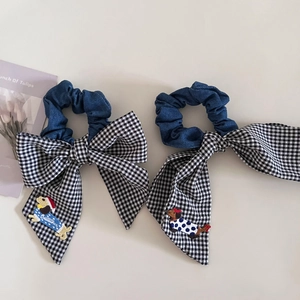 Detail of dachshund embroidery on blue denim scrunchie with black and white plaid bow