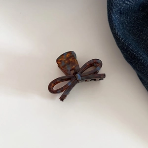 Close-up of tortoise shell pattern acetate bow hair claw clip on denim fabric background