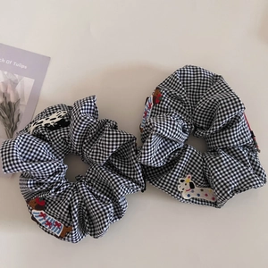 Close-up of black and white plaid hair scrunchies with cute embroidered dachshund dogs