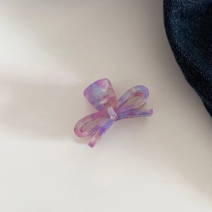 Detail view of purple marbled acetate bow hair claw clip on neutral background