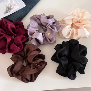 Détail d'un lot de 5 chouchous en satin de soie avec des petites plaques dorées de luxe