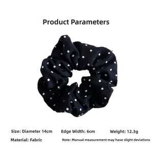 Détail d'un chouchou noir à pois montrant un diamètre de 14 cm et la texture du tissu