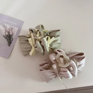 Detail of silk satin bow hair claws in sage green and dusty rose with acrylic clips